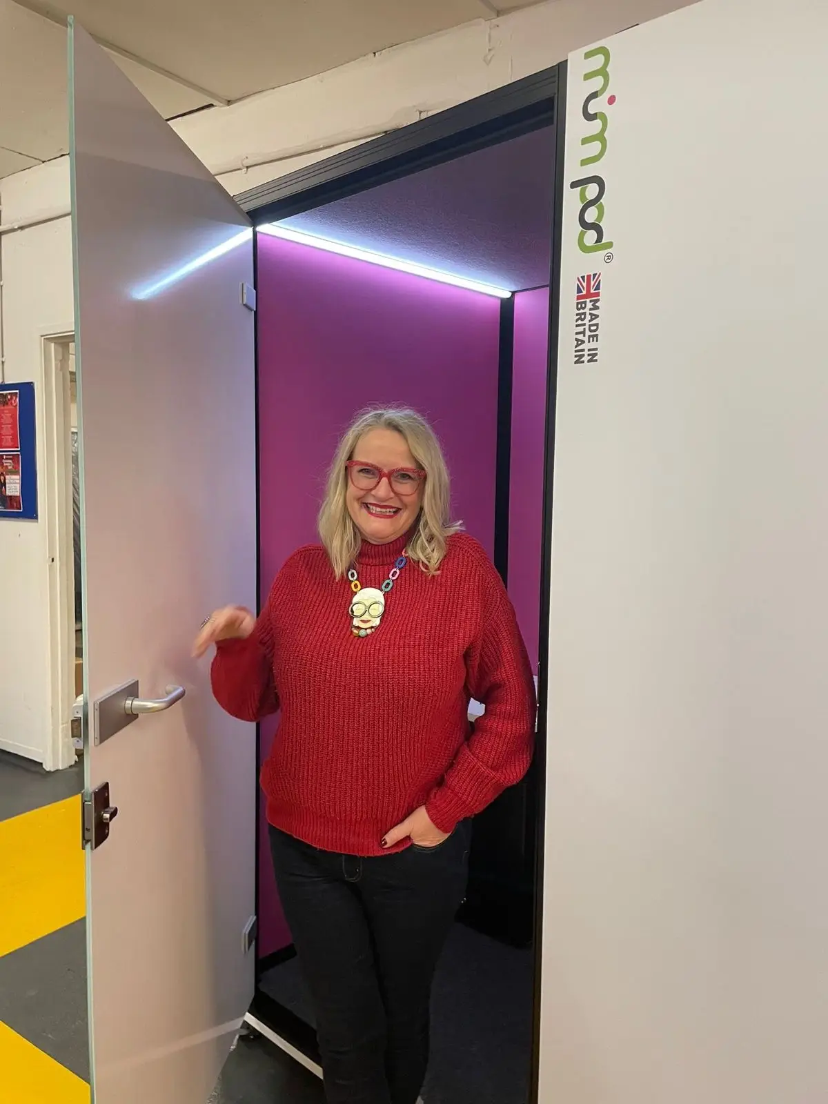MumPod CEO holds the door of small nursing room, lactation pod.